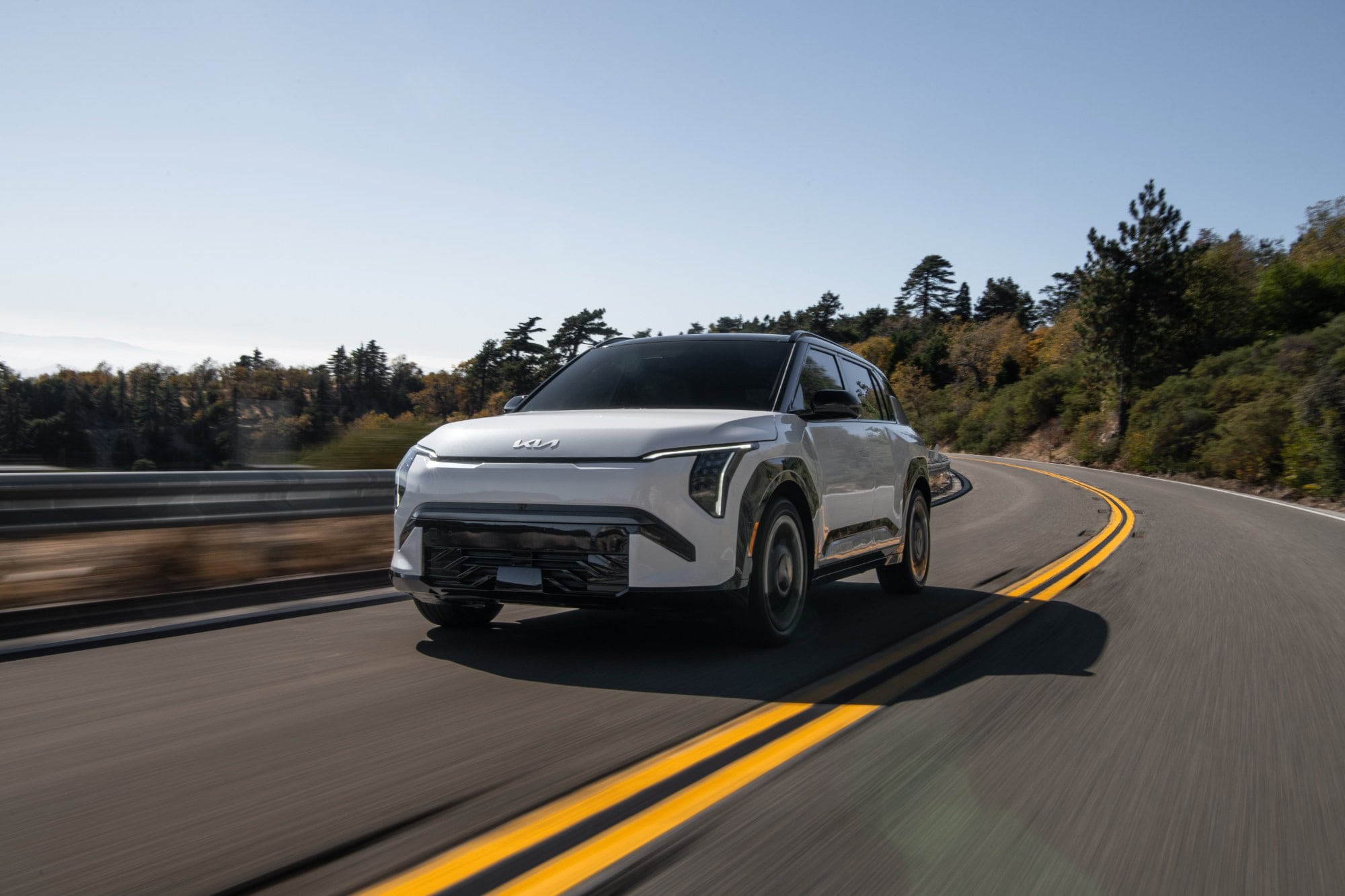 2027 Kia EV3 in white driving on a mountain road