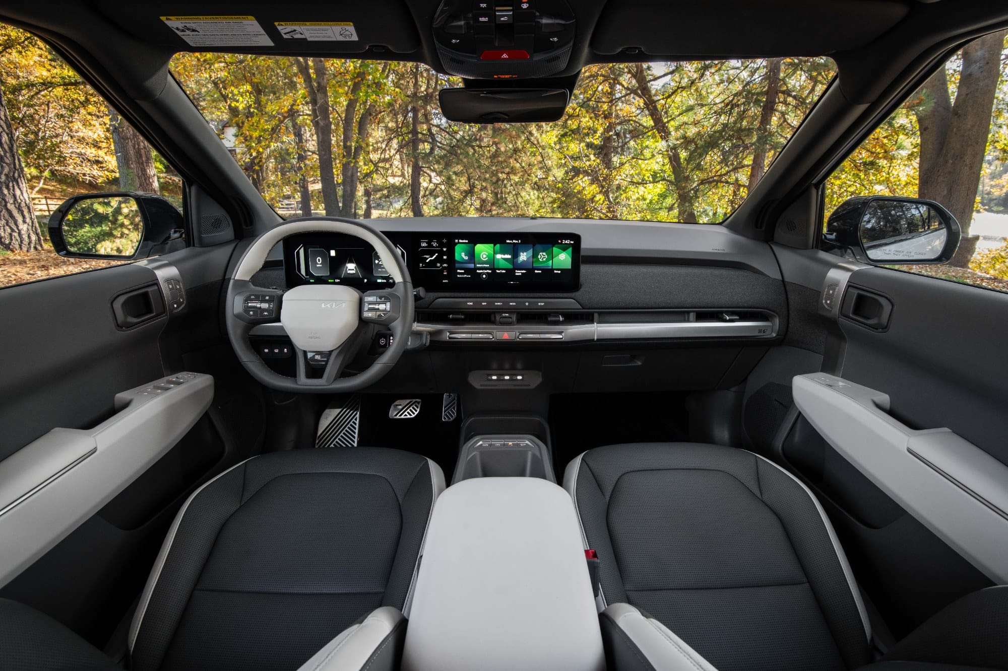 2027 Kia EV3 interior, dashboard and panoramic display viewed from the rear seat