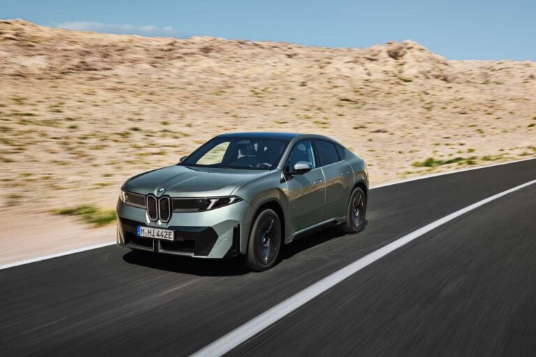 BMW iX4 in green, front three quarter view on a road