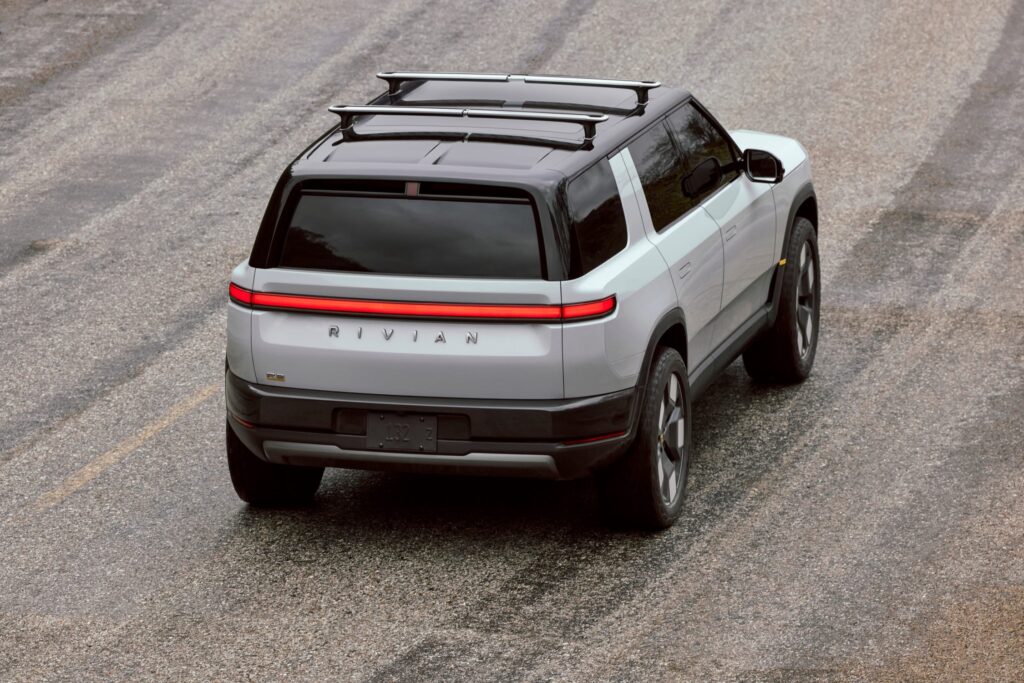 Rivian R2 in silver with roof crossbars, rear three quarter view from above