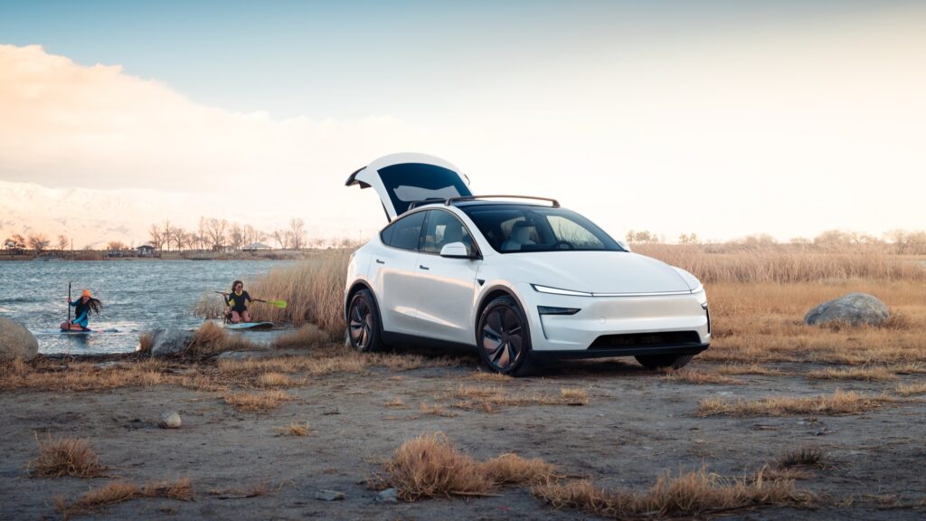 Tesla Model Y Premium in white with the power liftgate open beside a lake